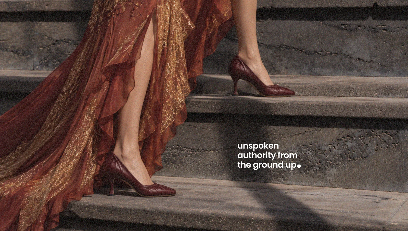 Street poster: an oxblood heel on concrete steps beneath the line 'unspoken authority from the ground up'