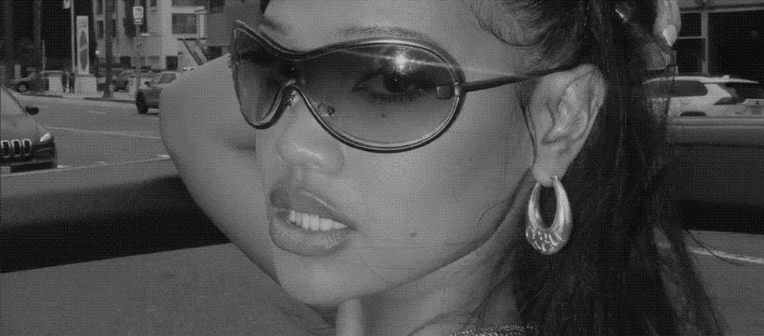 A woman in wraparound sunglasses wearing the Drop hoop, on a city street