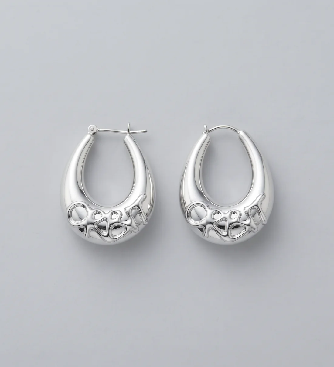 The Drop hoops, two polished silver hoops with the wordmark across their base