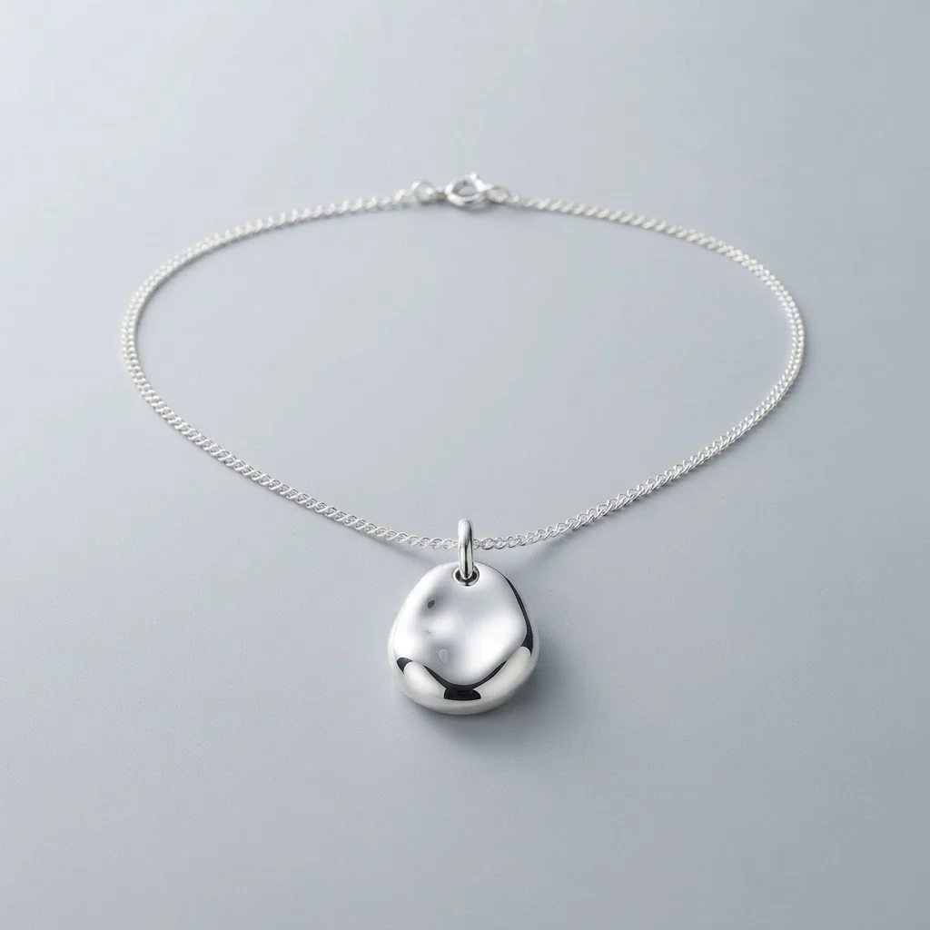 The Orbit pendant, a smooth silver pebble on a fine chain